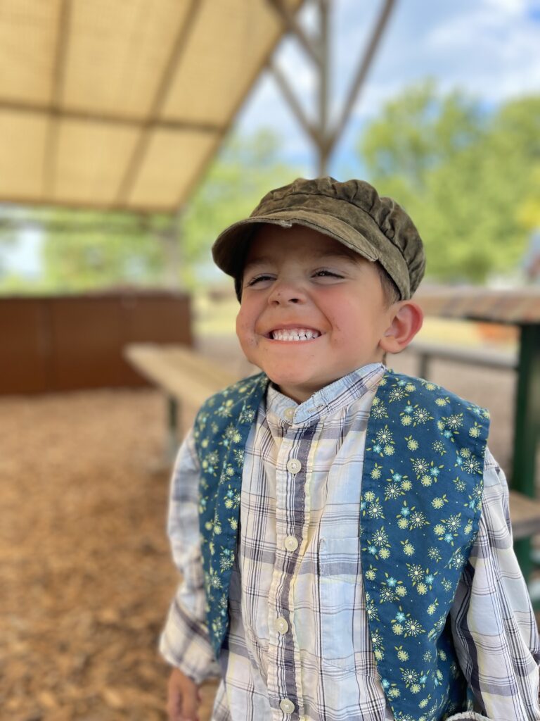 Young boy grinning as he dresses up in time period clothing from the 1800's in Nauvoo Illinois